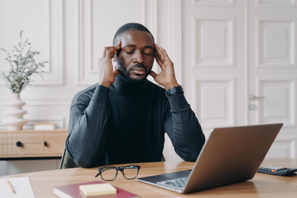 frustrated-tired-afro-american-man-office-worker-with-closed-eyes-trying-to-concentrate-at-workplace